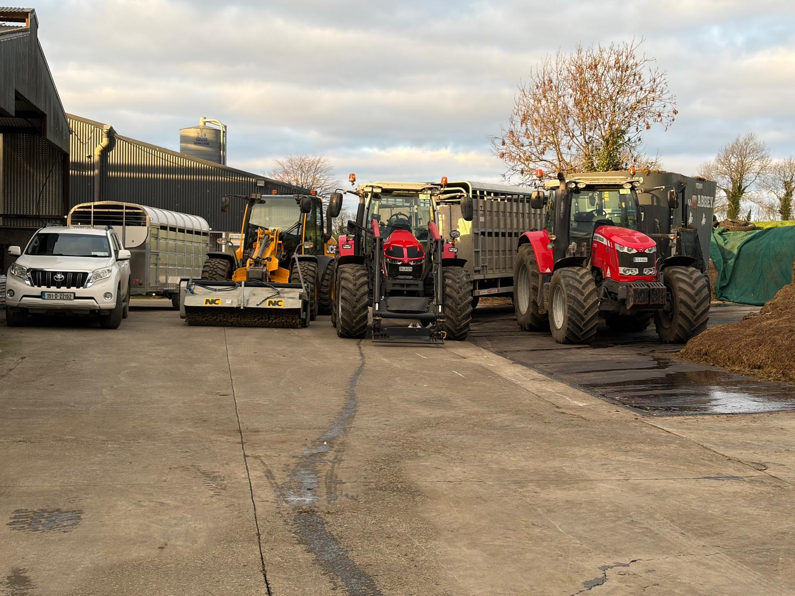 Fleet of farm machinery and tractors lined up in the farmyard