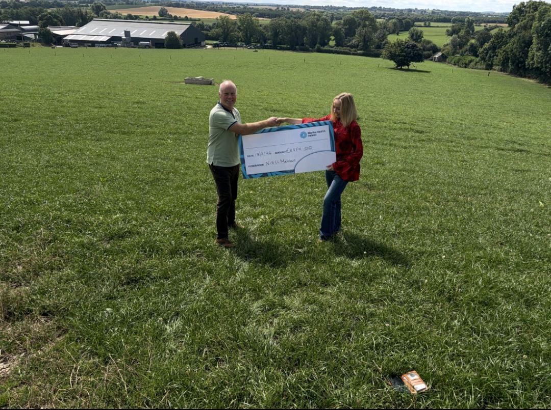 Niall Matthews presenting a cheque for Mental Health Ireland on the hilltop fields at Tully with panoramic farmland views